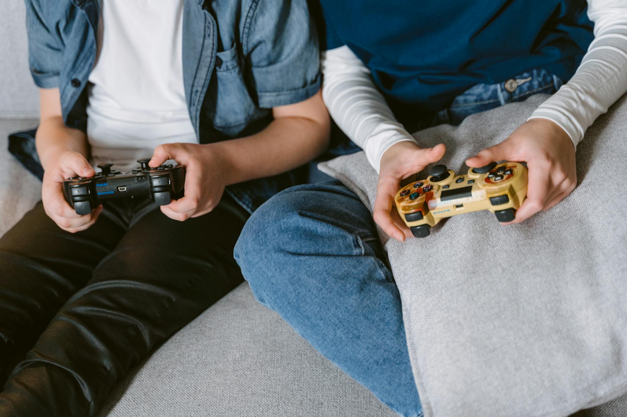 Two teenagers absorbed in console gaming indoors, focused on controllers.